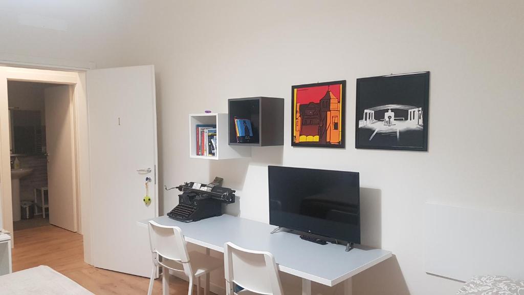 una camera con scrivania, TV e macchina fotografica di Affittacamere Risorgimento a Lecco