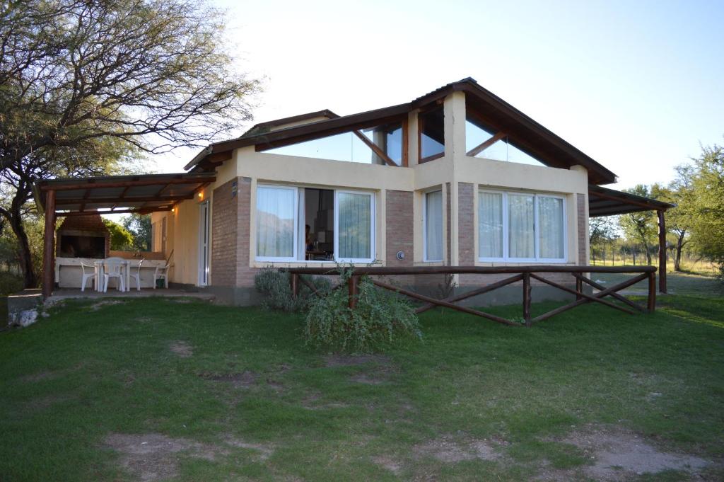 una casa con porche y patio de césped en Cabañas Tintihuasi en Villa Las Rosas
