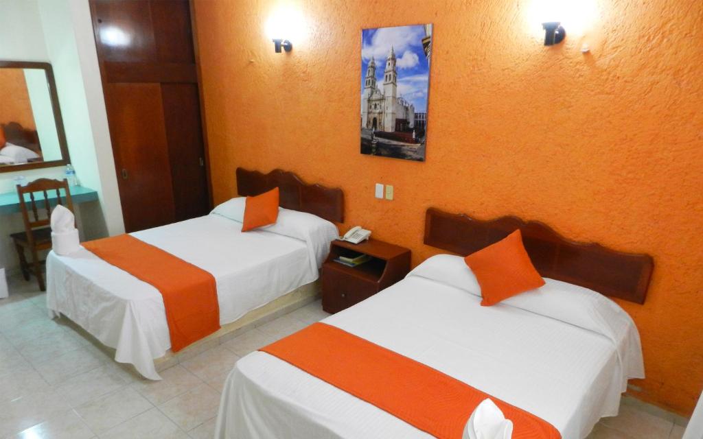 Hotel Uxulkah في كامبيش: غرفة فندق بسريرين بجدران برتقالية