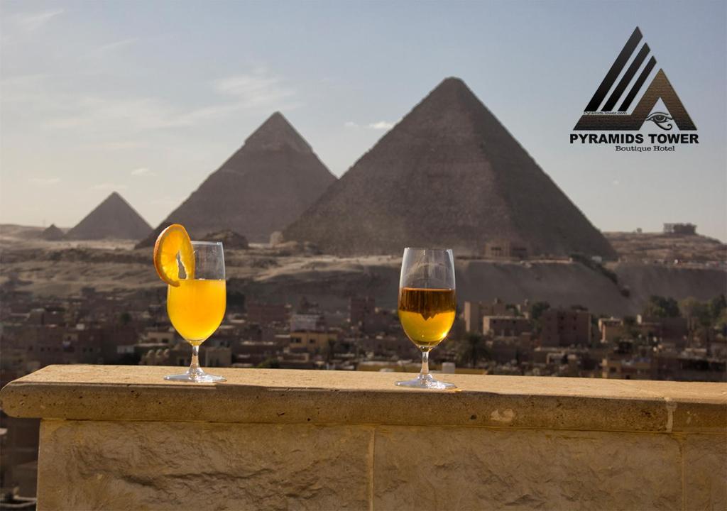 two glasses of wine sitting on a ledge with pyramids at PYRAMIDS TOWER Inn in Cairo