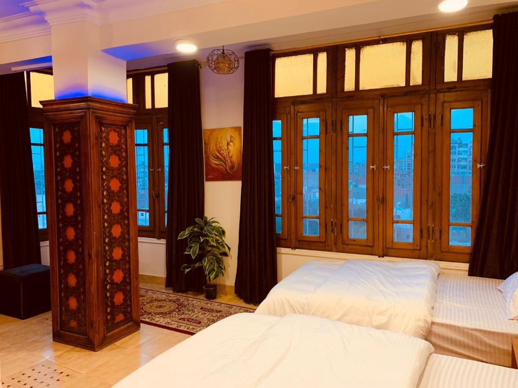 a bedroom with a bed and large windows at Draz pyramids view Bed & breakfast in Cairo