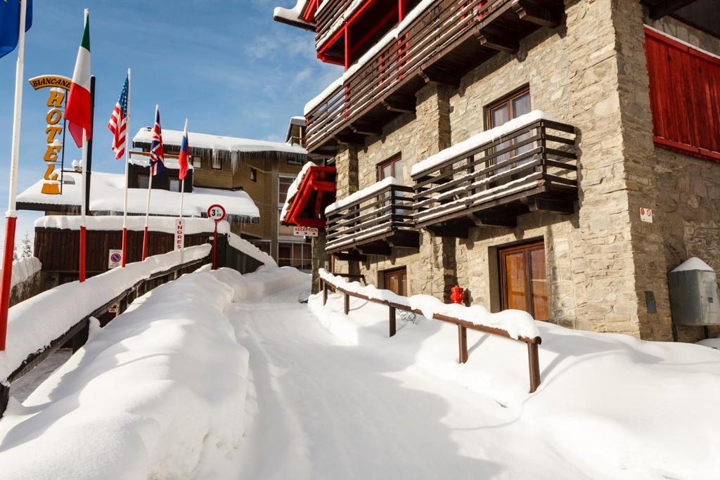 a snow covered building with flags in front of it at Hotel Biancaneve in Sestriere