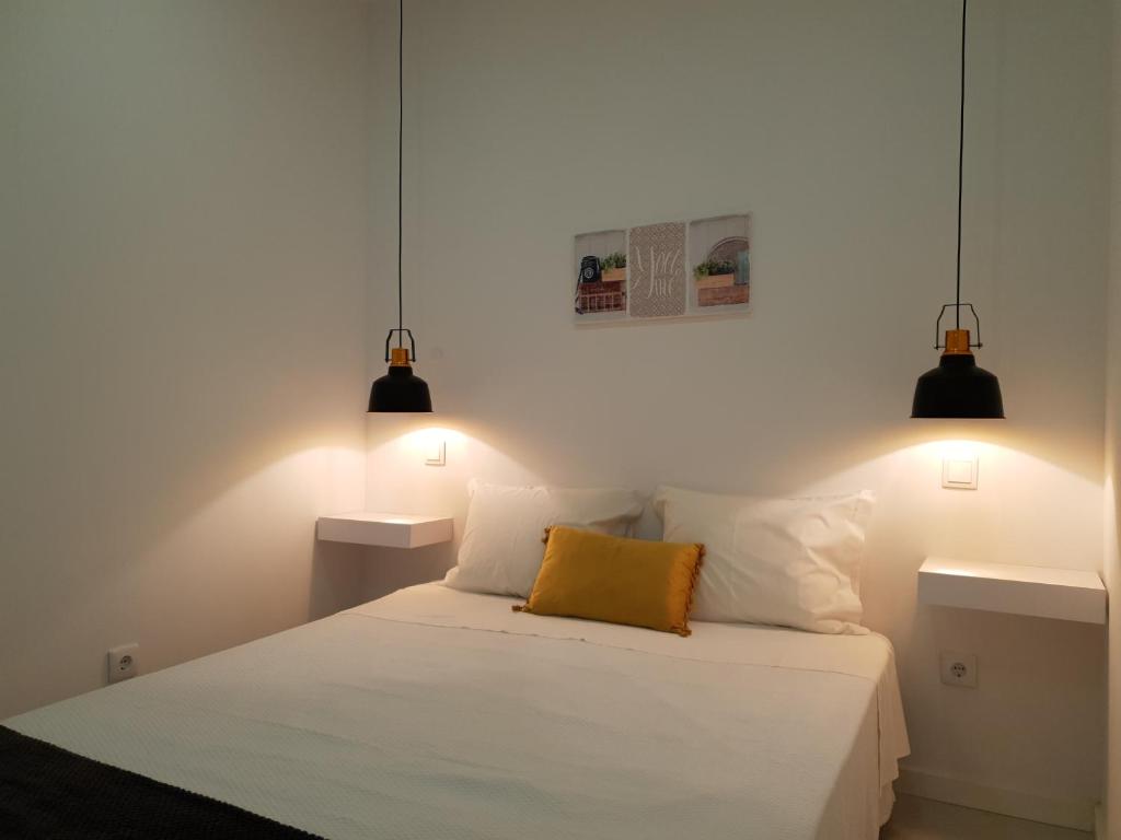 a bedroom with a white bed with two lights at Beco's House - Suits in Ílhavo