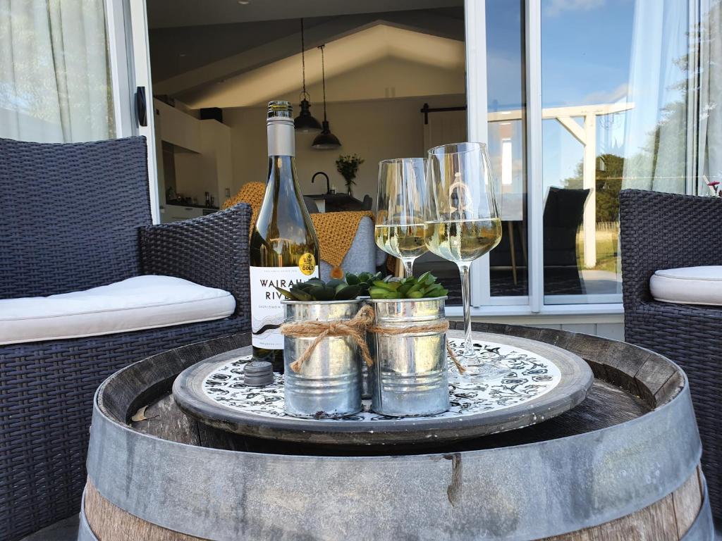 a table with a bottle of wine and a glass at Garden View Cottage in Carterton
