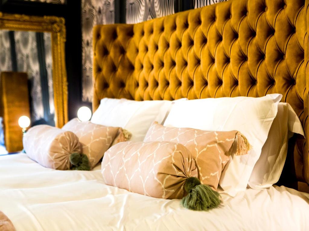 a bed with white pillows and a yellow headboard at Maison Parfaite YO1 - Exquisite 400 Year Old, City Centre Townhouse in York