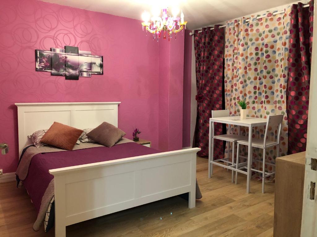 a bedroom with pink walls and a bed and a table at Chambres privées Calais Ferry-Port-Place d&#39;armes in Calais