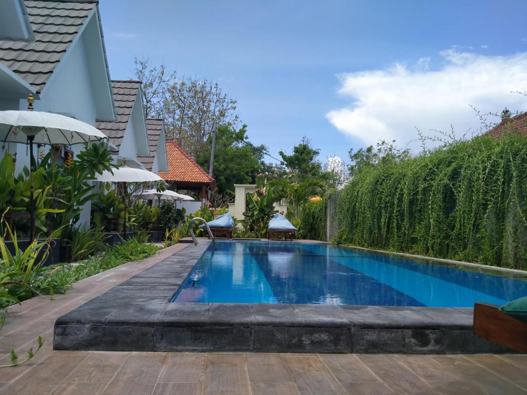 a swimming pool in a villa with a hedge at PITAMATA VILLAS in Nusa Penida