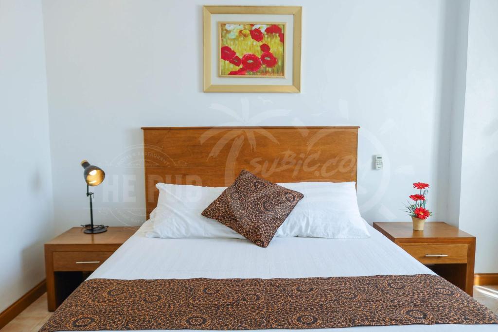 Schlafzimmer mit einem Bett mit einem Kopfteil aus Holz in der Unterkunft The Pub Hotel in Olongapo