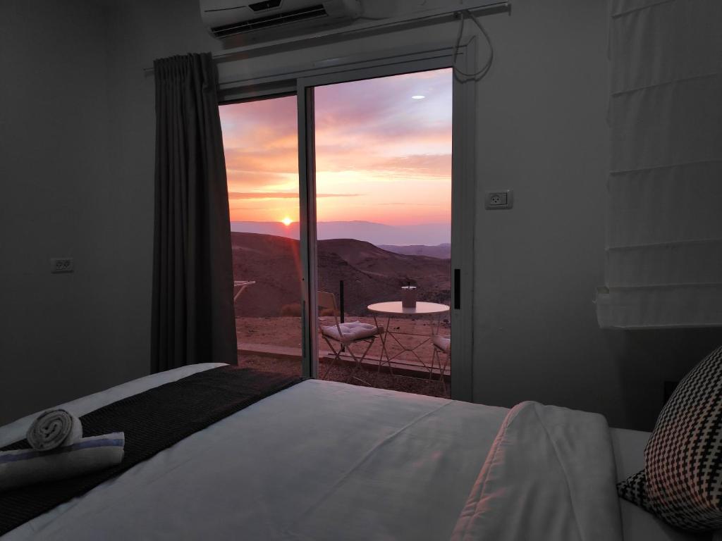 a bedroom with a bed and a window with a view at Dead Sea Desert's Edge in Arad