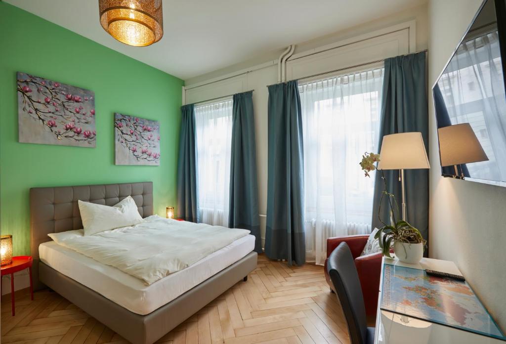 a bedroom with a bed and a desk and windows at Hotel Ambassador in Solothurn