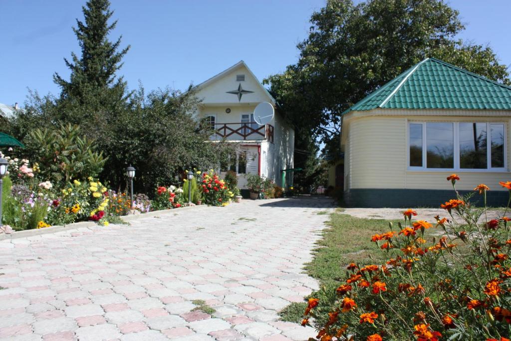 a house with a brick driveway and flowers in front of it at Jamilya B&B Guest House in Karakol