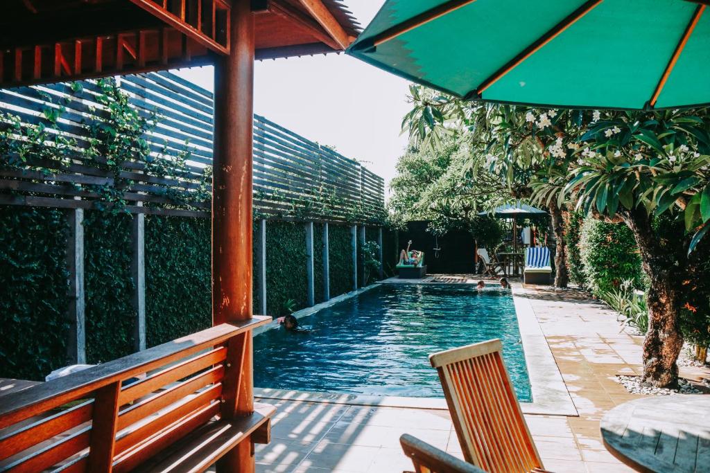 a swimming pool with a bench and an umbrella at D'sawah Villa in Tanah Lot