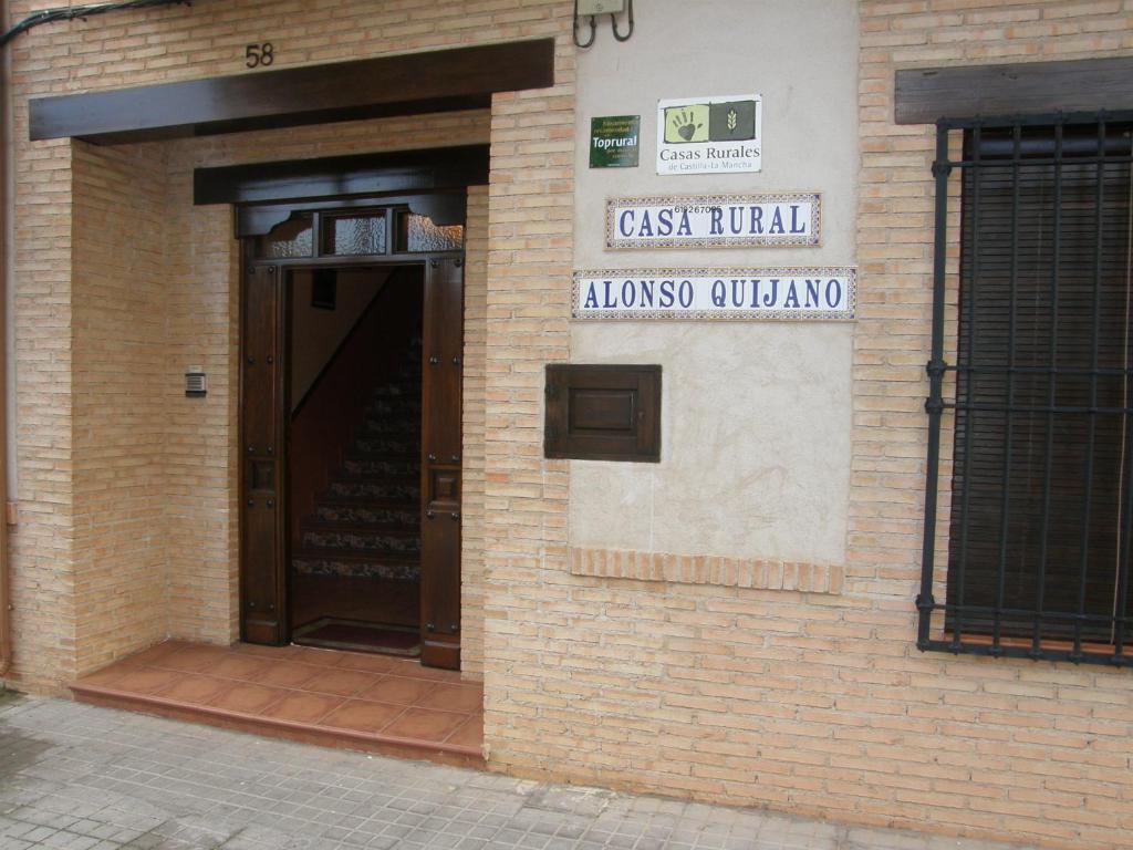 un edificio de ladrillo con una puerta y una señal en él en Casa Rural Alonso Quijano en Argamasilla de Alba