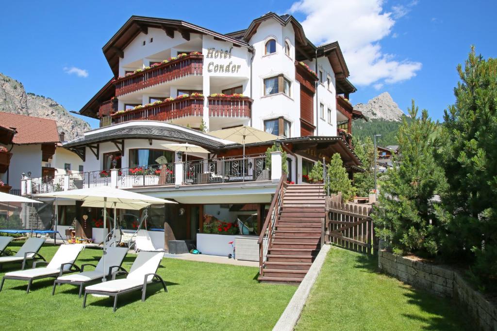 um grande edifício com espreguiçadeiras e guarda-sóis em Hotel Condor em Selva di Val Gardena