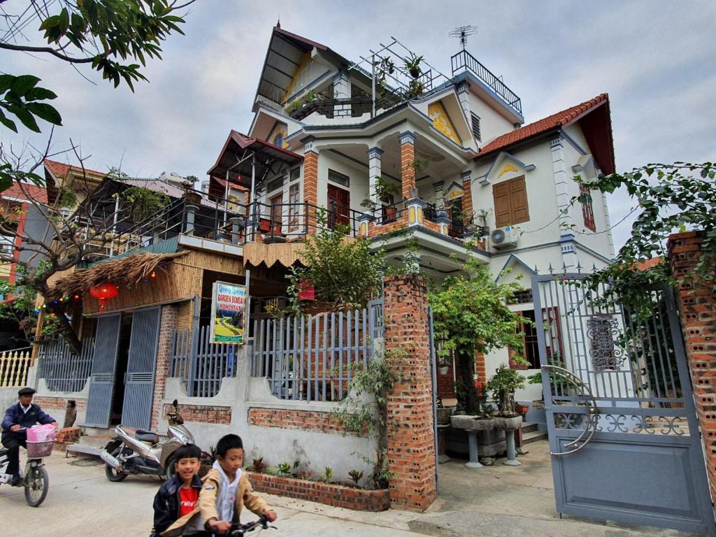 ein Haus mit zwei Kindern davor in der Unterkunft Quang Quang Garden Bonsai Homestay in Ninh Bình