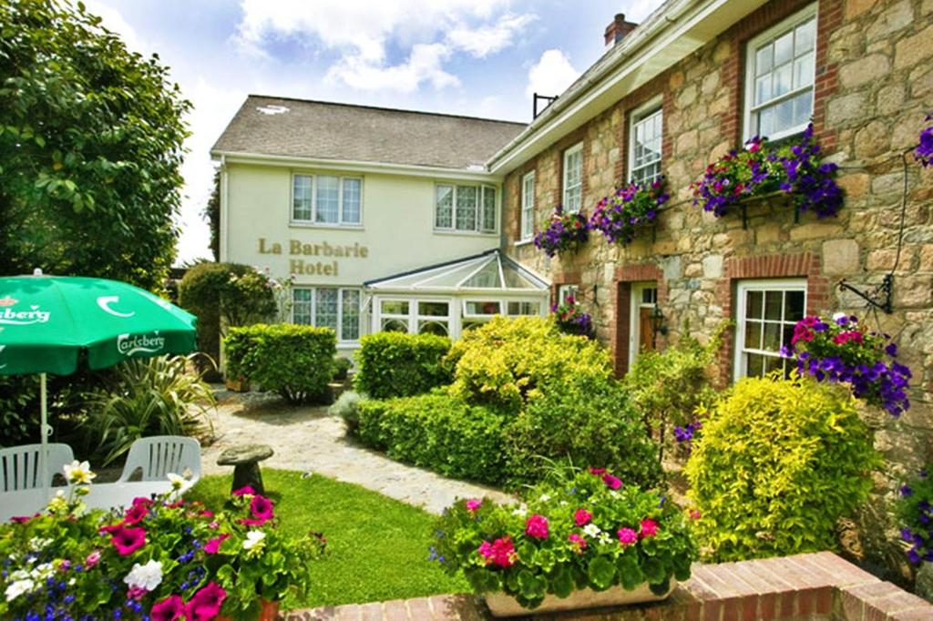 a garden in front of a building with flowers at La Barbarie Hotel by Eight Continents in St. Martin Guernsey