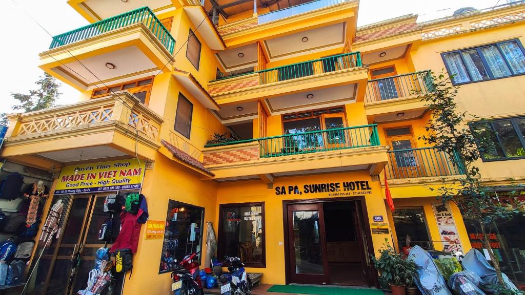 a yellow building with balconies and motorcycles in front of it at Sapa Sunrise Hotel in Sapa