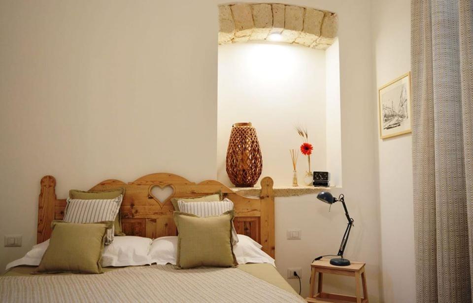 ein Schlafzimmer mit einem Bett mit einem Kopfteil aus Holz in der Unterkunft B&B Cose Belle in Capurso