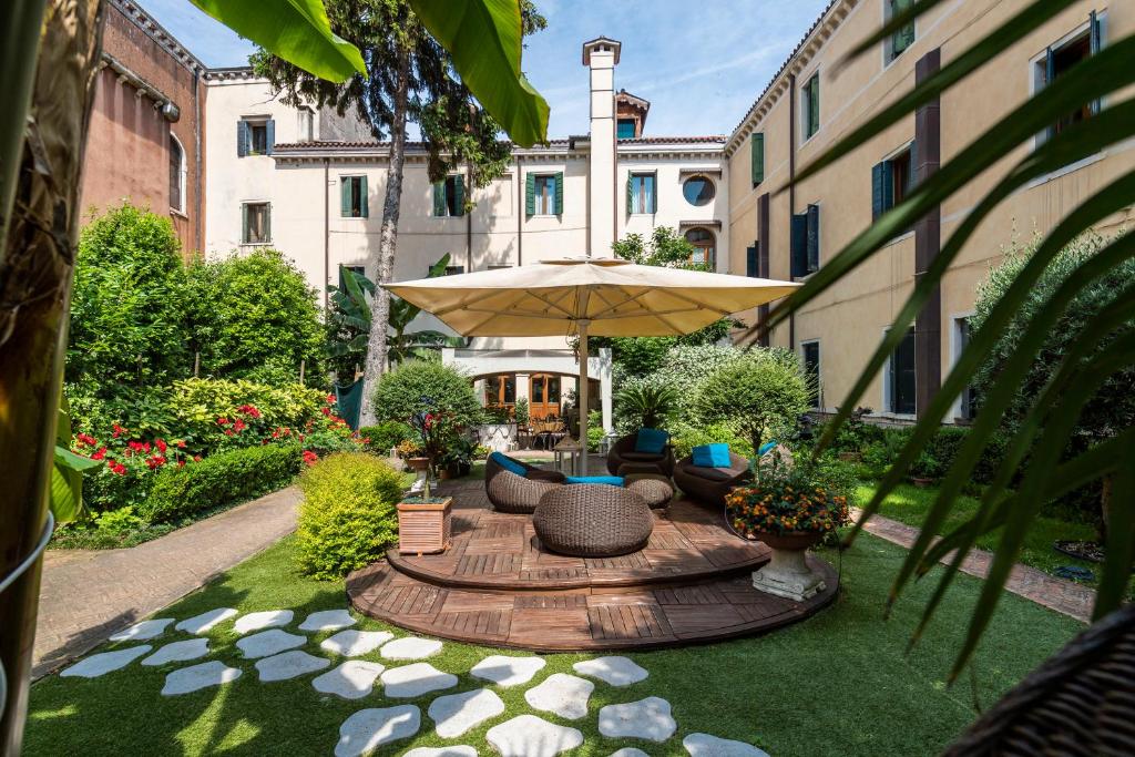 a patio with a table with an umbrella and chairs at Hotel Abbazia in Venice