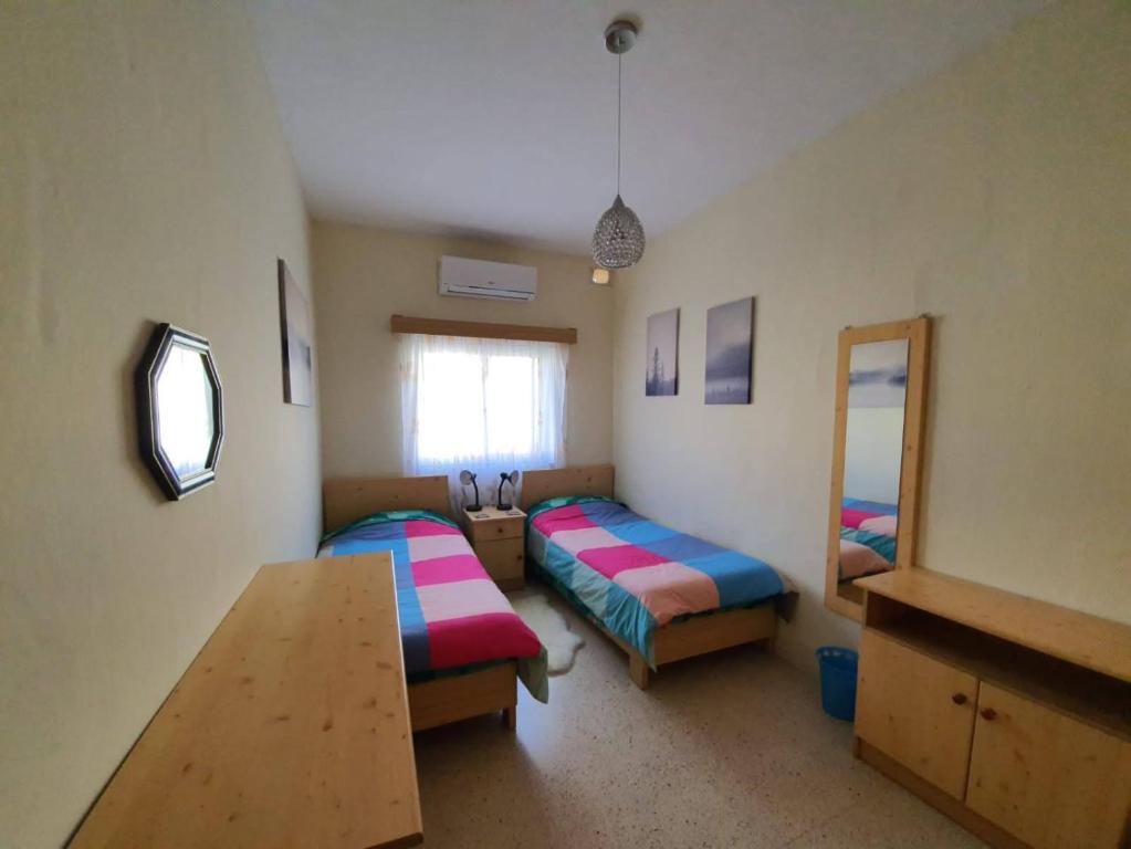 Cette chambre comprend 2 lits, une table et un miroir. dans l'établissement Kennedy Court - PRIME LOCATION - Bus Terminus, à San Pawl il-Baħar