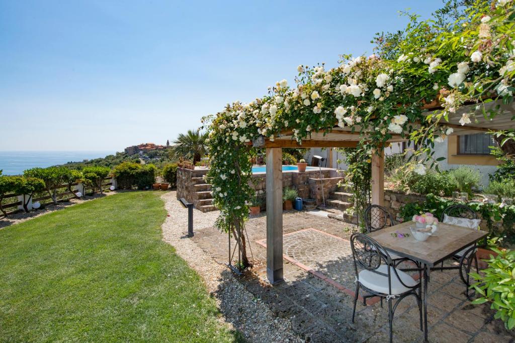 a garden with a table and a pergola with roses at Villa Annetta in Poggi
