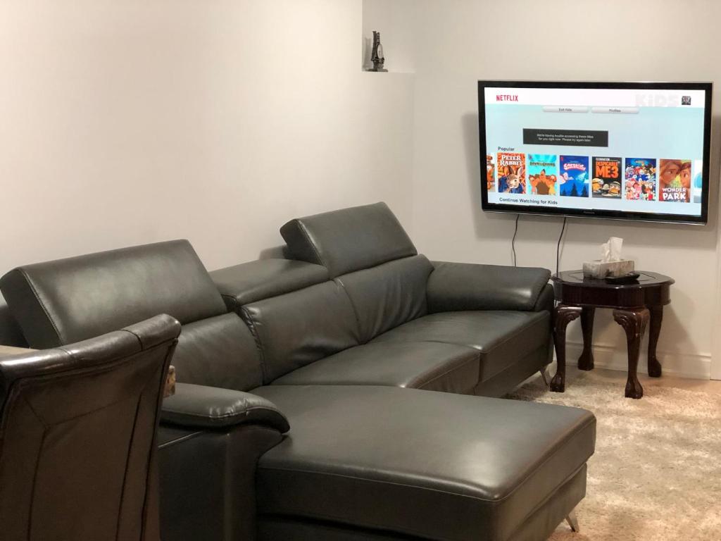 a living room with a leather couch and a flat screen tv at Rose palace in Mississauga