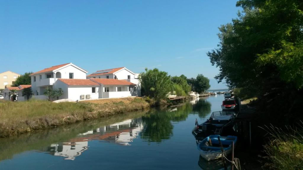 une rivière avec des maisons et des bateaux dans l'eau dans l'établissement Apartments Noa Nin Ždrijac, à Nin