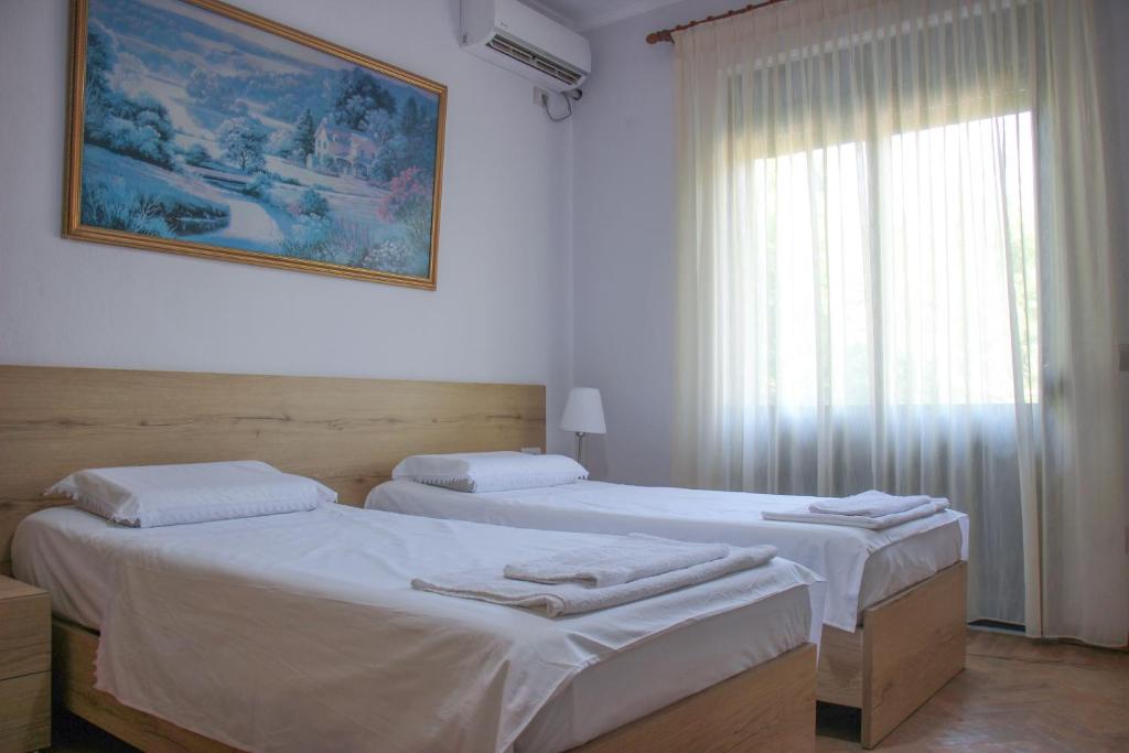 two twin beds in a room with a window at Ballo Apartments in Gjirokastër