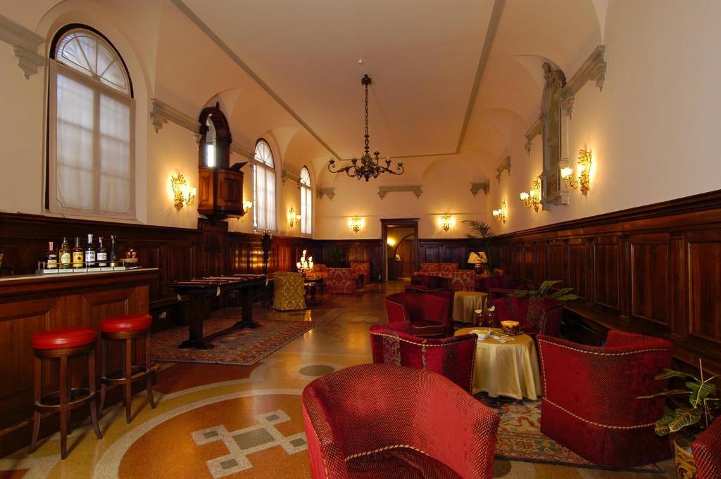 a restaurant with red chairs and a bar in a room at Hotel Abbazia in Venice