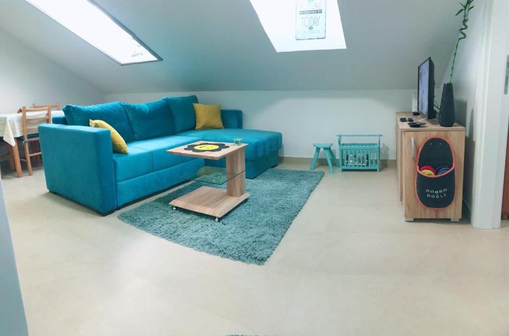 a living room with a blue couch and a table at Apartman Santorini in Novi Sad