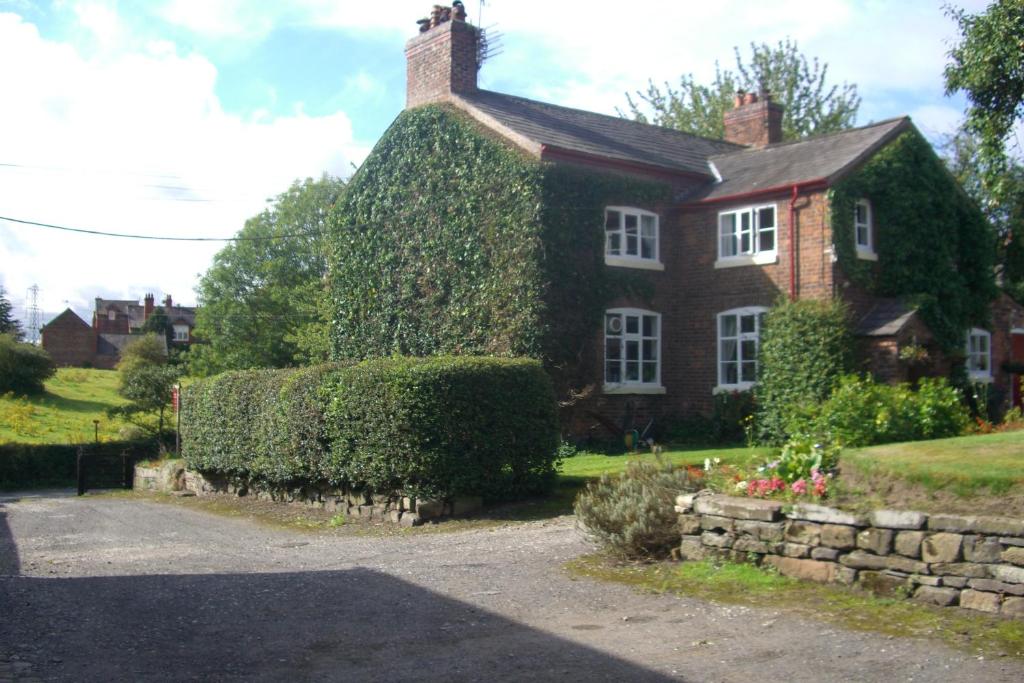 Una casa con hiedra a un lado. en Ash Farm Country House en Little Bollington