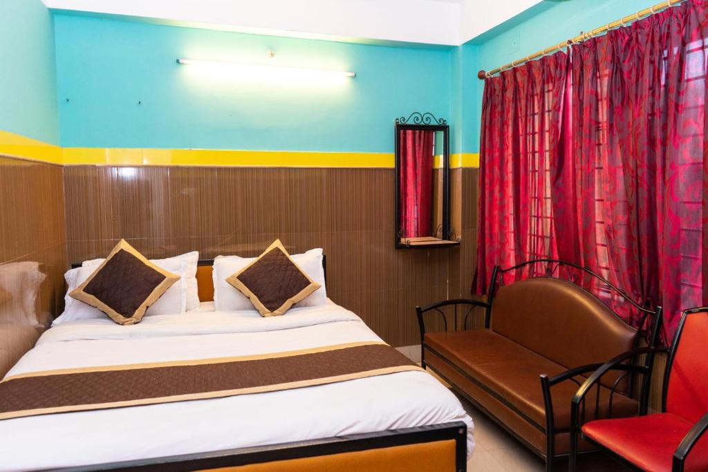a hotel room with a bed and a chair at Tirupati Lodge NJP in Siliguri
