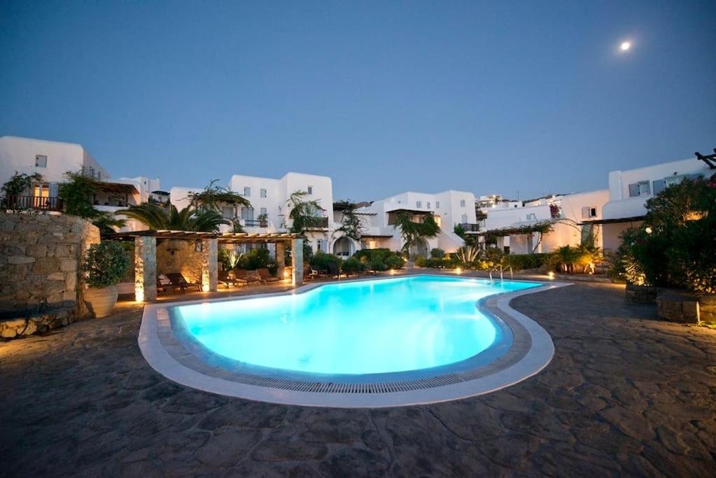 uma grande piscina à noite com edifícios ao fundo em Our Beautiful House in Ornos, Mykonos em Ornos
