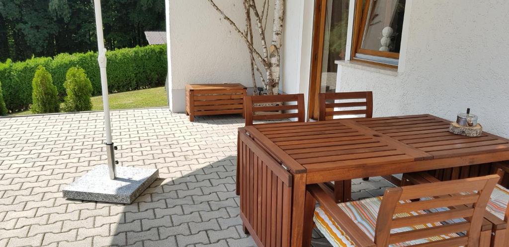 una mesa de madera y sillas en un patio con sombrilla en Ferienwohnung Betula, en Fürstenstein