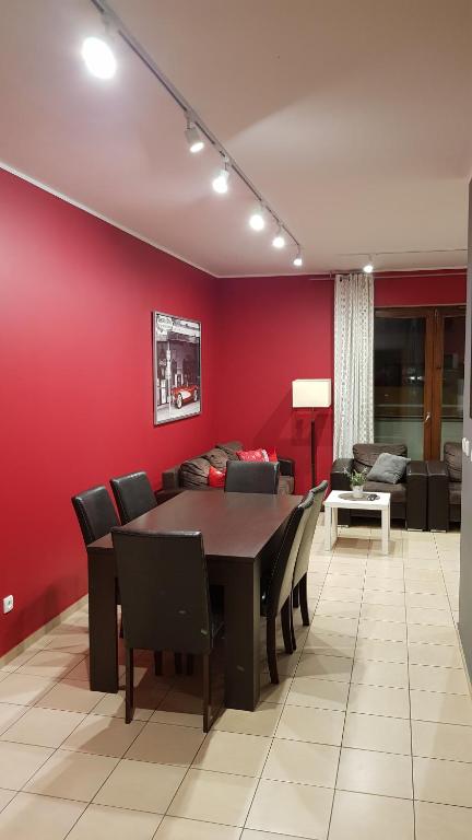a dining room with a red wall and a table and chairs at Frog Apartment - 2 bedrooms and living room in Świnoujście
