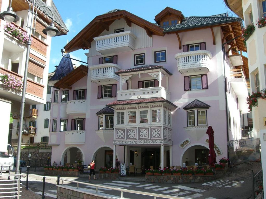 um edifício cor-de-rosa com uma varanda numa rua em Ciasa Mancin Suite-Apartments em Moena
