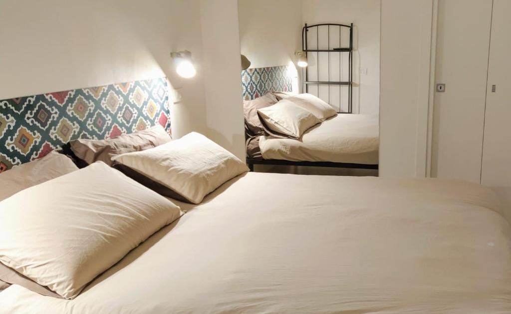 una camera con 2 letti con cuscini bianchi di La Nicuzza-#historicalhouse a Agrigento