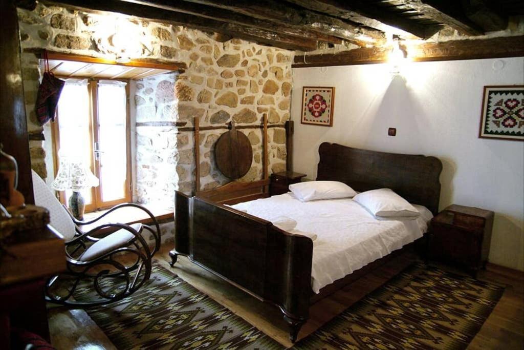 um quarto com uma cama grande numa parede de pedra em ΤΑ ΚΩΝΣΤΑΝΤΑΔΙΚΑ em Arnaía