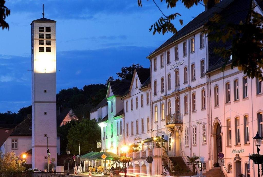 a building with a clock tower in a town at night at Hotel zum Schwan in Bad Karlshafen