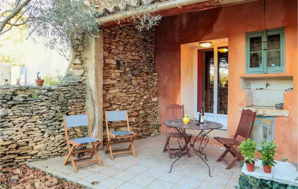 un patio avec une table et des chaises et un mur en pierre dans l'établissement Cozy Apartment In Villes Sur Auzon, à Villes-sur-Auzon