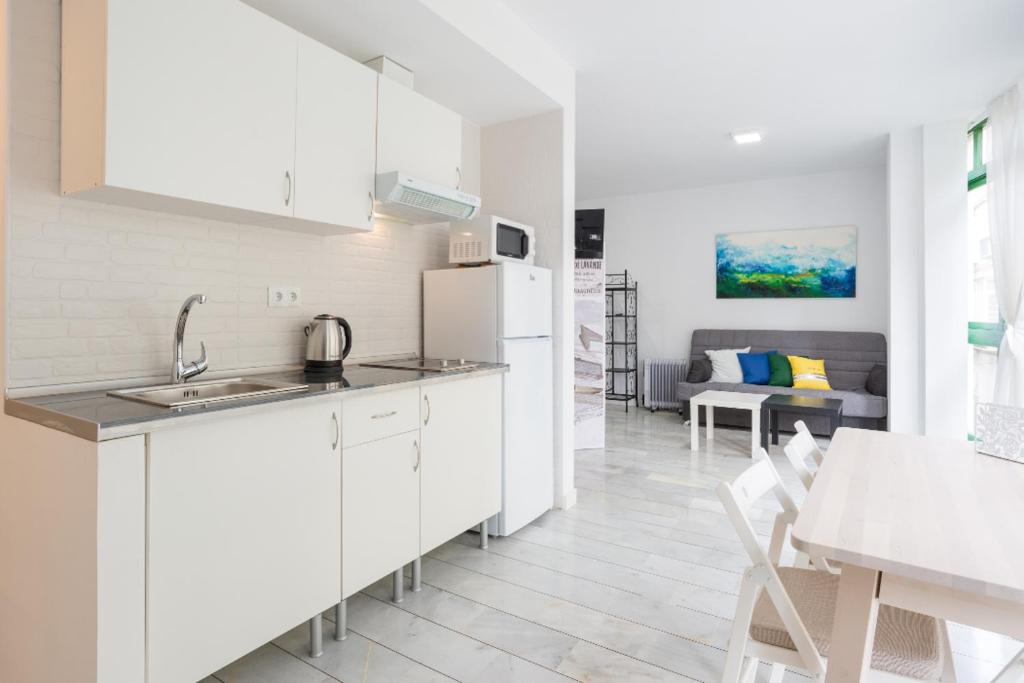 biała kuchnia ze zlewem i stołem w obiekcie Livemálaga Panaderos Old Town w Maladze