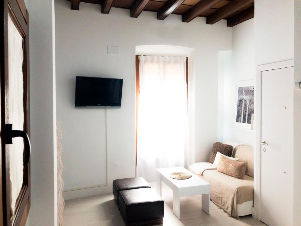 ein Wohnzimmer mit einem Sofa und einem TV an der Wand in der Unterkunft Pasaje de Amores in Sevilla