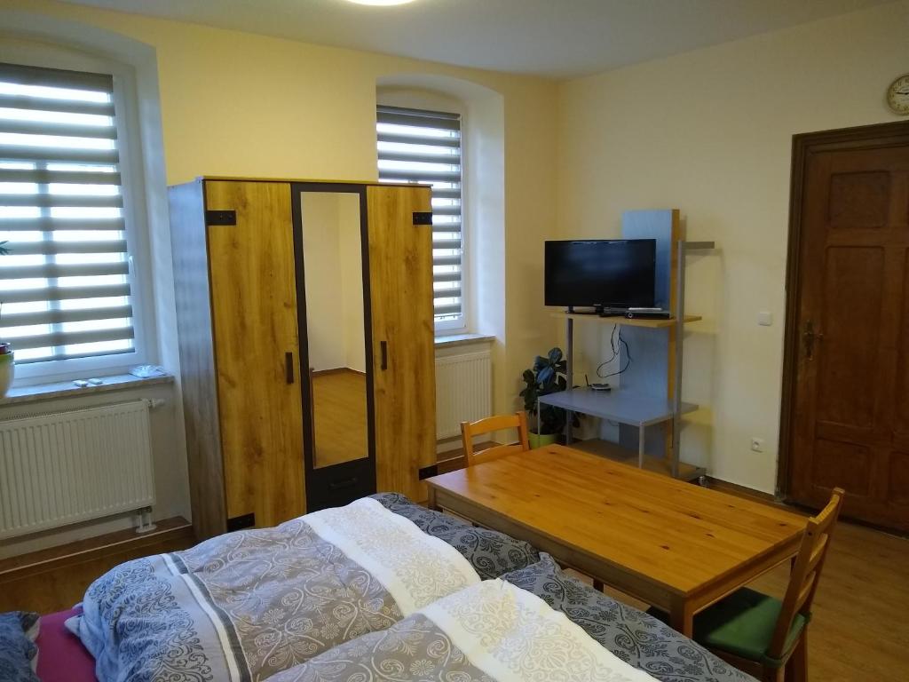 a bedroom with a bed and a table and a tv at Ferienwohnung Schleich in Starkenberg