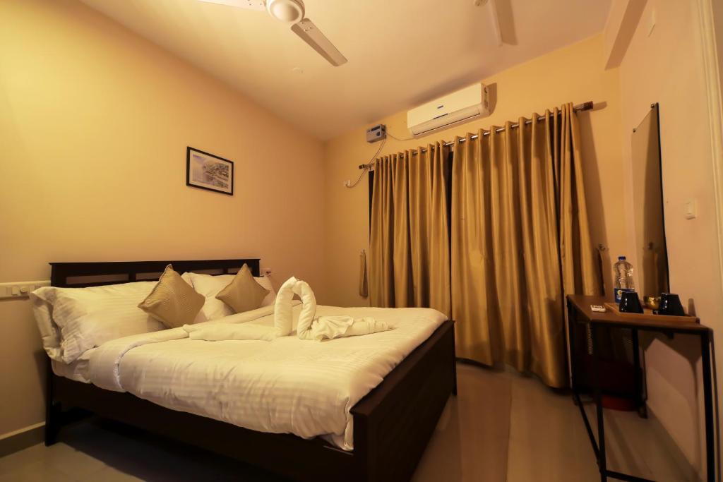 een slaapkamer met een bed met witte lakens en een raam bij Misty Rosa Luxury Serviced Apartments in Kottayam