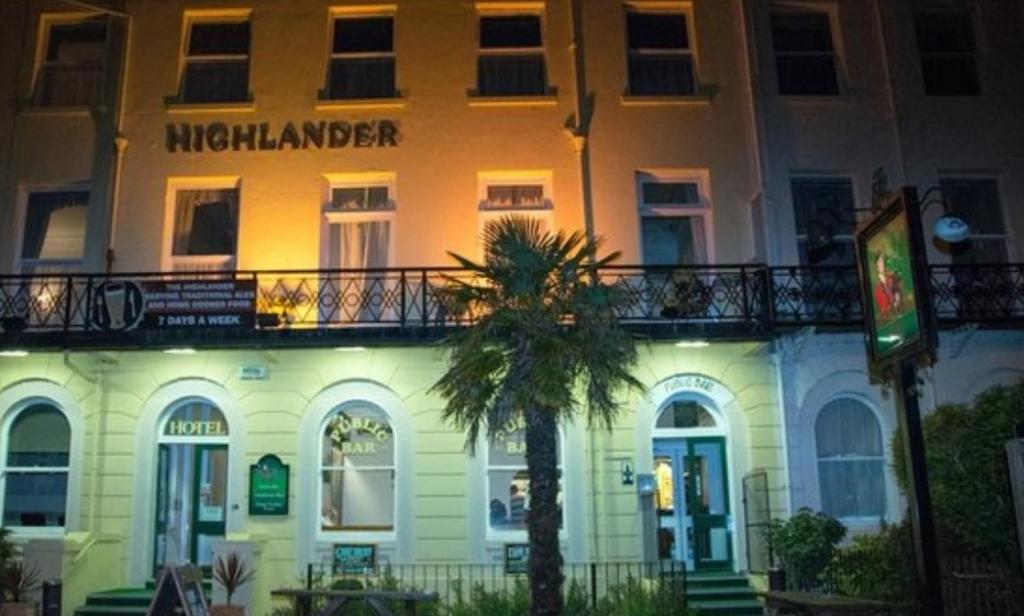 a building with a palm tree in front of it at Highlander Hotel in Scarborough