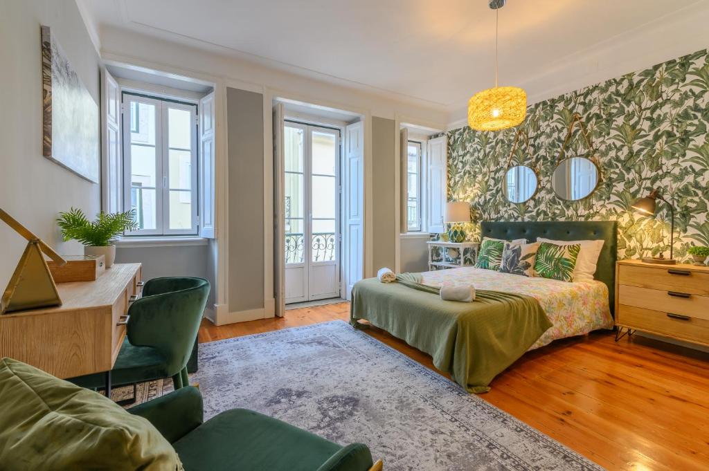 um quarto com uma cama, uma secretária e janelas em Sant´Ana Apartment em Lisboa