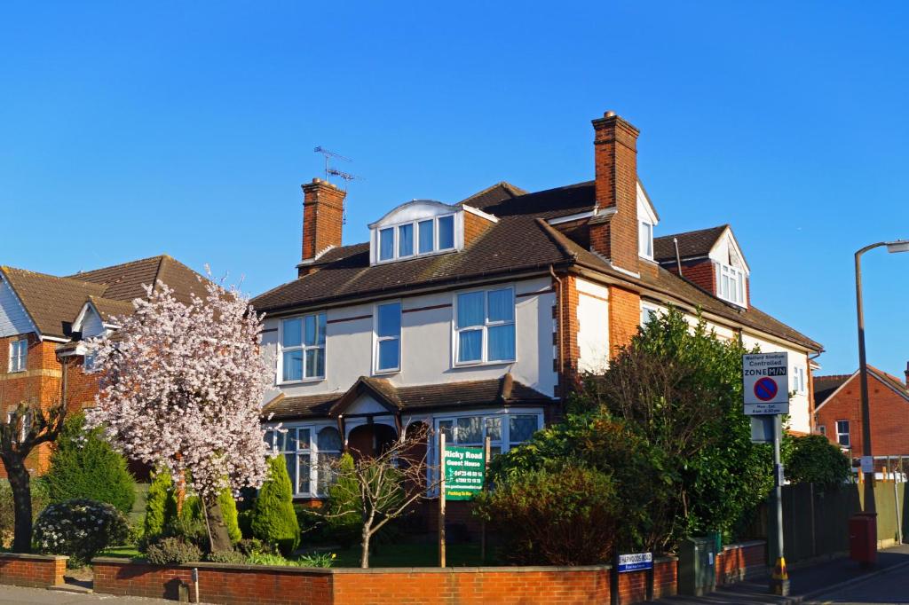 una casa con un albero da fiore di fronte di Ricky Road Guest House - "Wizard Studio Room" Available to Book Now a Watford