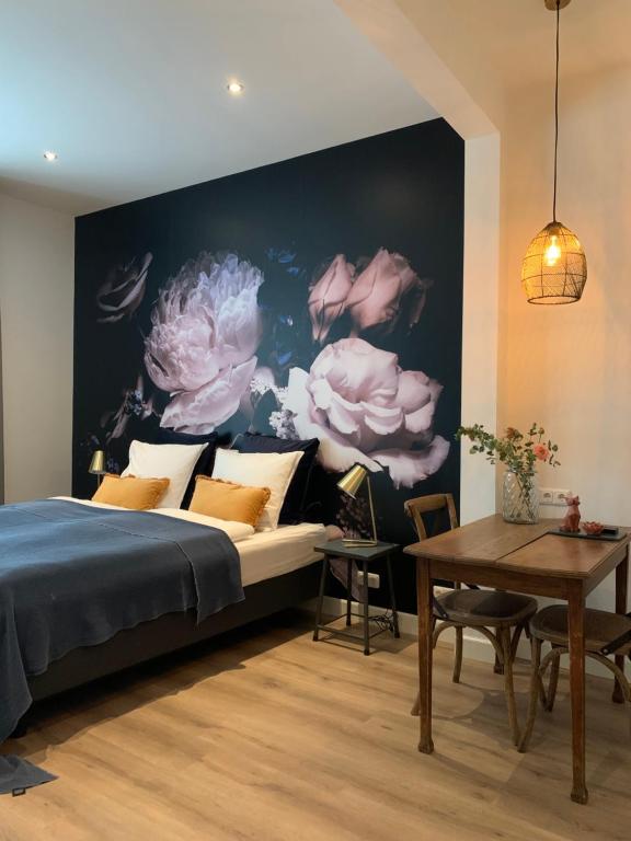 een slaapkamer met een bed en een muur met bloemen bij De Vossenheuvel in Venlo