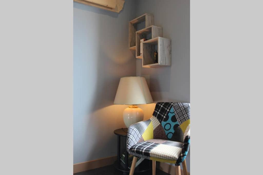 a living room with a chair and a lamp at GITE PARIS - Appartement in La Clayette