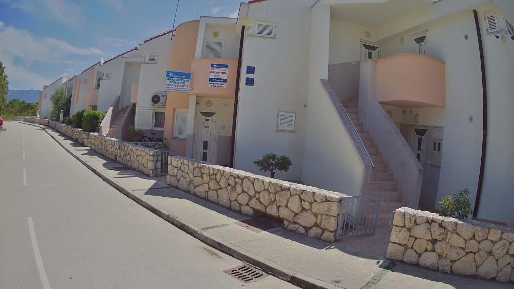 a row of buildings on a street with a stone wall at Apartments Pag-Travel in Novalja